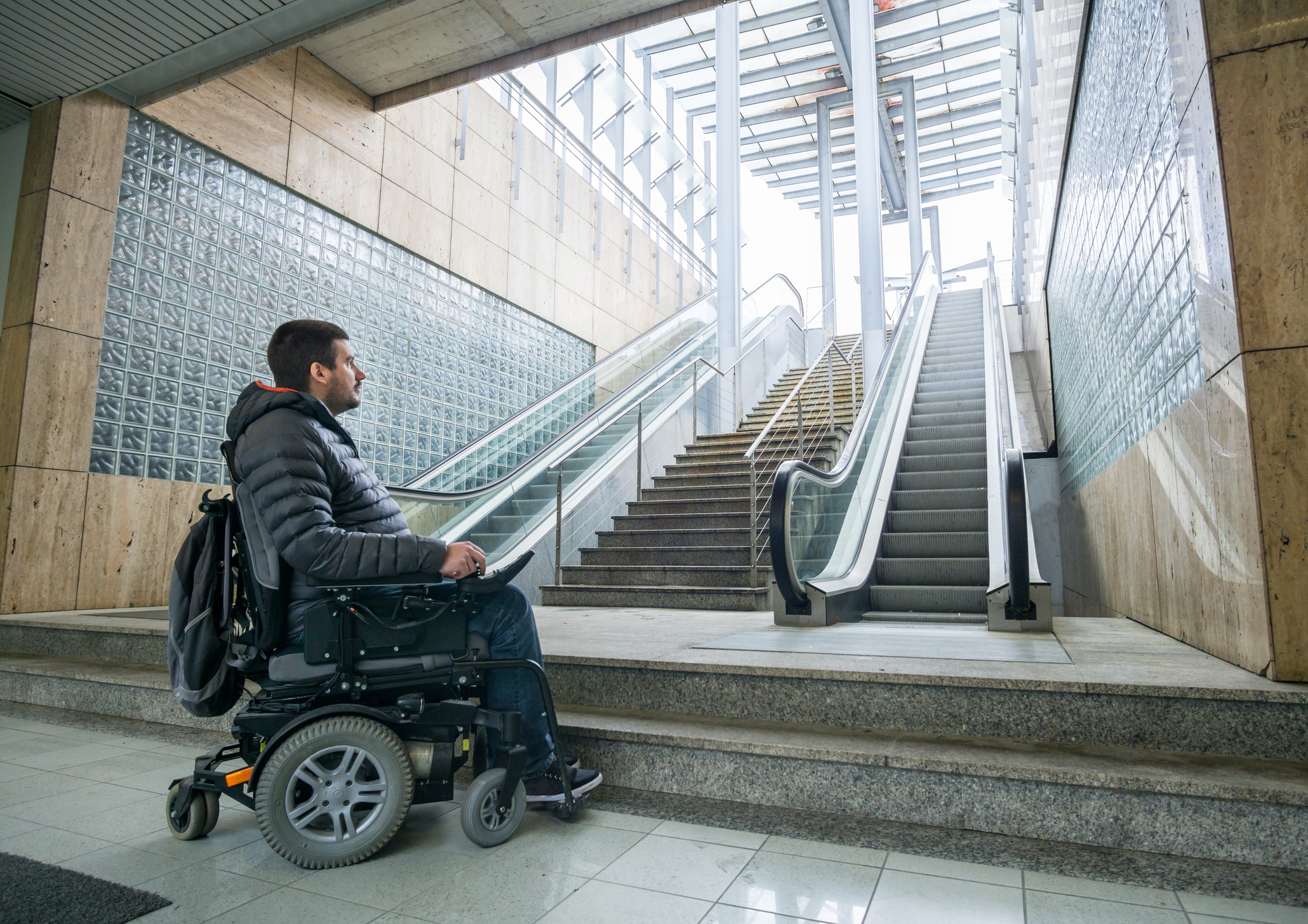 Disabled Man On Wheelchair In Front Of escalator and staircase