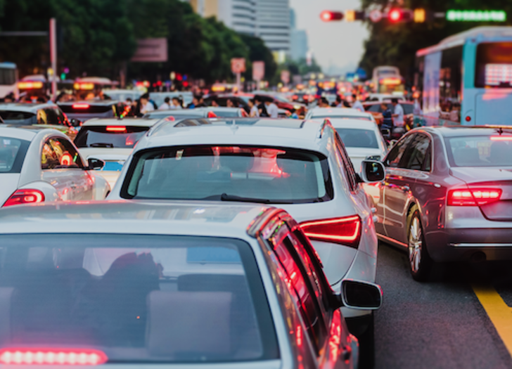 Cars and buses navigate heavy traffic on a busy road.