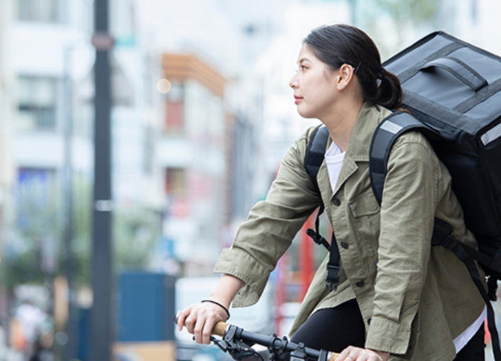 Delivery woman on ebike in busy city street