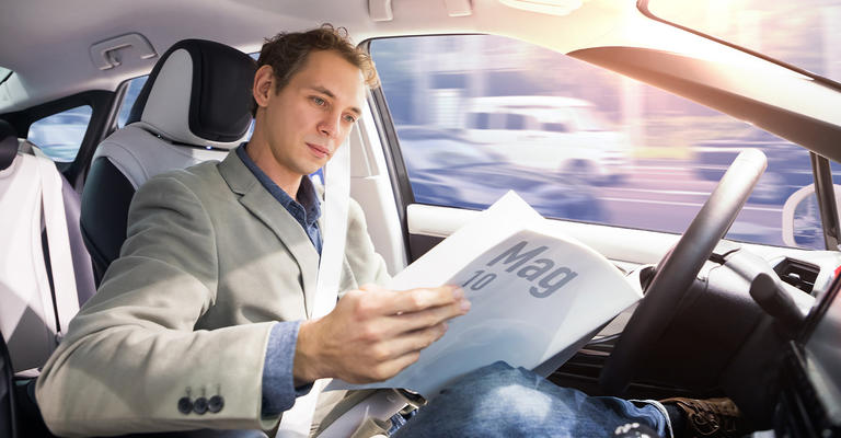 man in car reading magazine