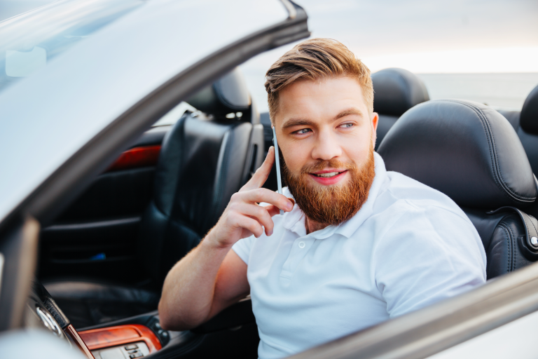 Male driver sitting in a car while talking on his phone