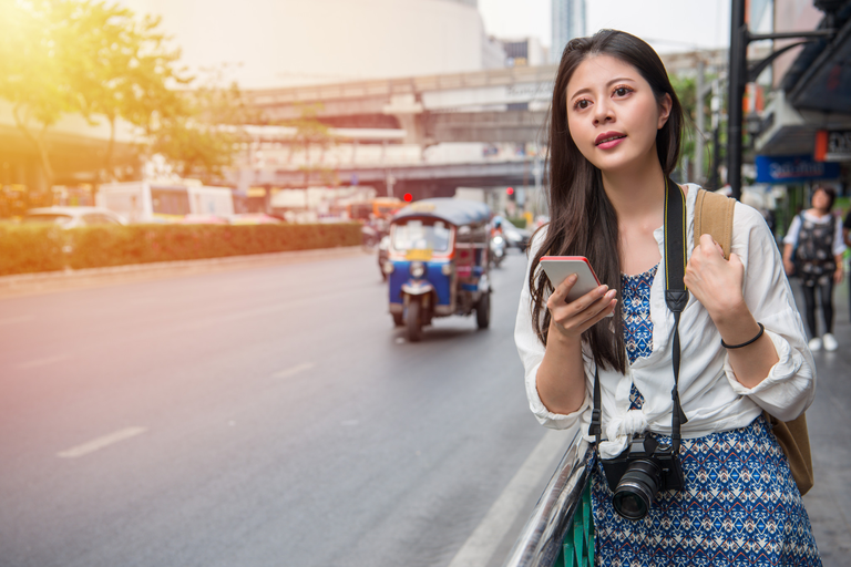 A woman in Thailand attempts to hail a taxi on a crowded street