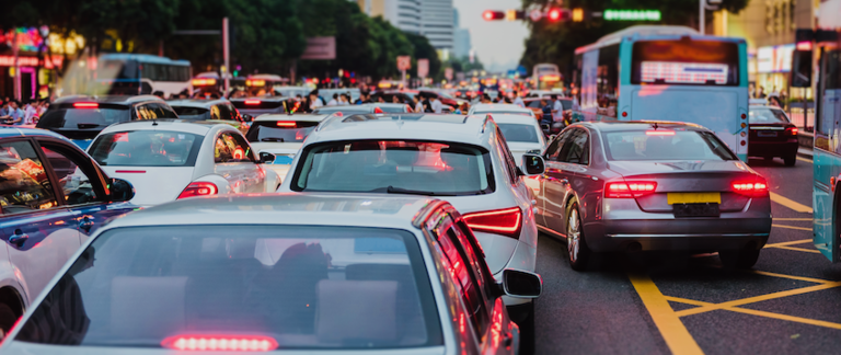 Cars and buses navigate heavy traffic on a busy road.