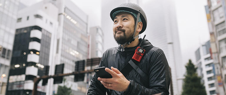 Man on ebike with helmet checks phone for routing in busy city street