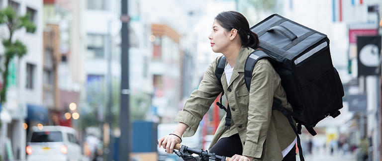 Delivery woman on ebike in busy city street