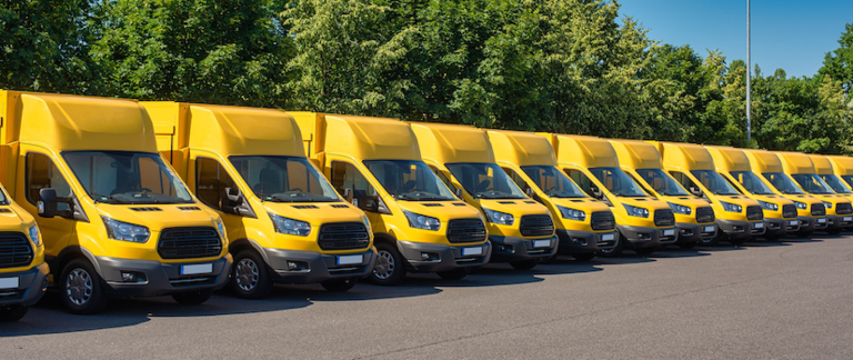 A row of bright yellow delivery trucks lined up in a parking lot.