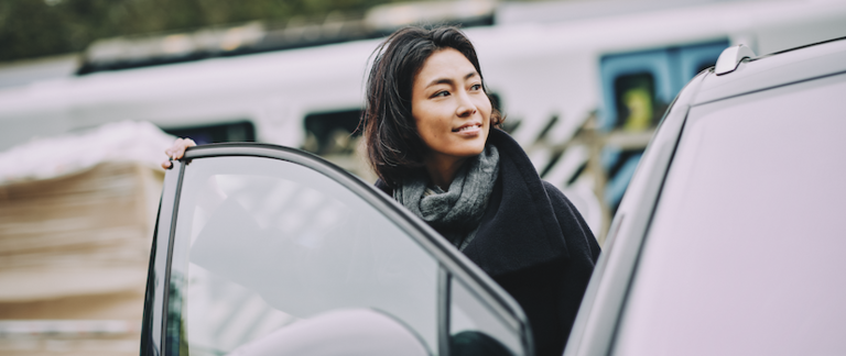 A woman driver about to get into the driver's seat of her car.