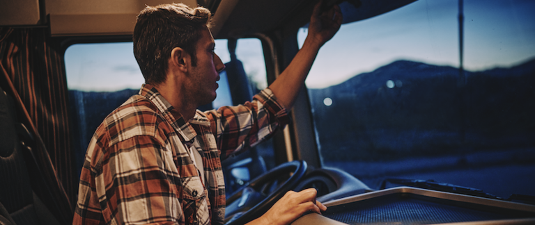 A male driver climbs into his truck at night.