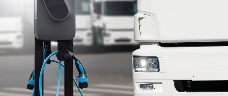 A close-up of an electric truck charging at a charging station.