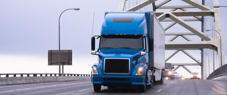 A semi truck driving over a bridge.