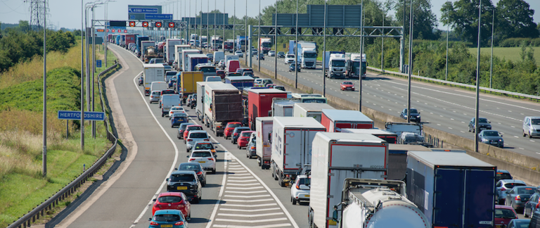 A line-up of cars and trucks stuck in traffic on a highway.