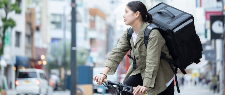 A woman on a cargo bike delivering packages in a city.
