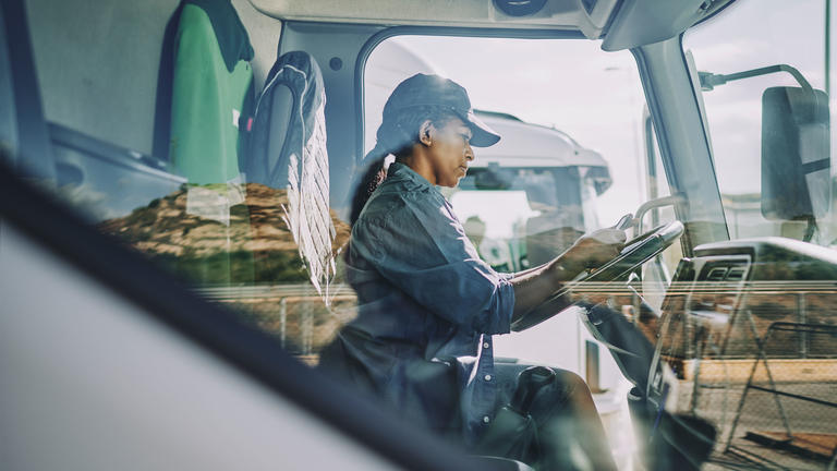 Woman in cab of truck with hands on steering wheel