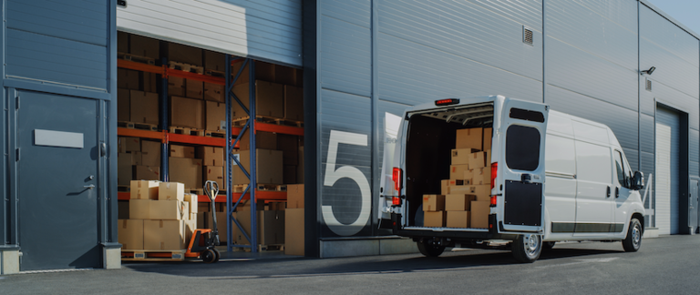 A delivery van is loaded with packages from a warehouse.