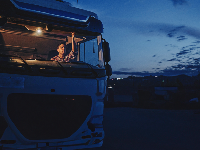 A driver prepares to drive his truck at dusk.