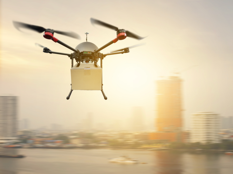 A drone carrying a package flies to its delivery destination.