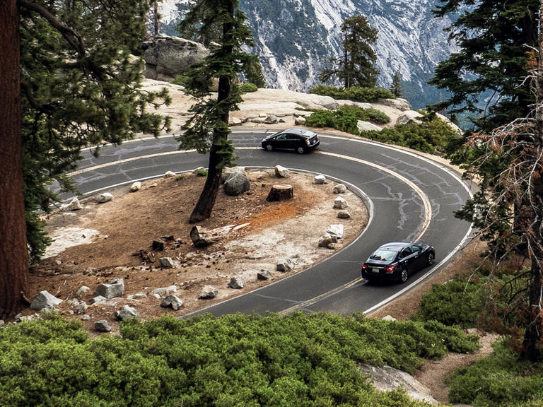 Two cars drive along a windy mountain road.