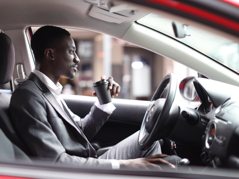 A man sips coffee while using the automated driving features in his car.