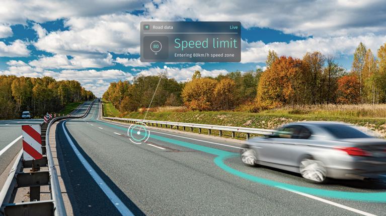 Car driving on the highway using connected navigation and driver assistance to receive speed limit data alerts.