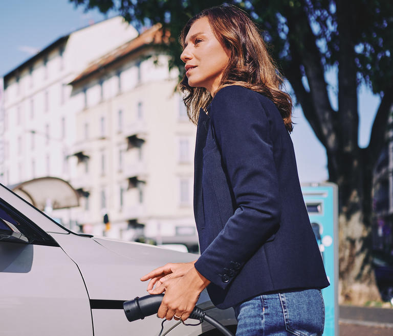 woman at charge station charging a vehicle
