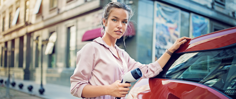 A woman charging her electric vehicle at a charging station.