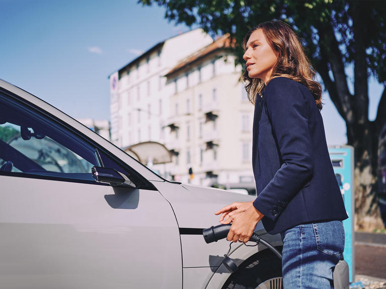 A woman plugs in her electric car at am EV charge point.