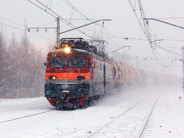 A freight train travels on a snowy track.